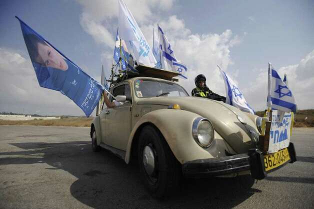 A 1974 Volkswagen Beetle is adorned with Israeli flags and portraits of 