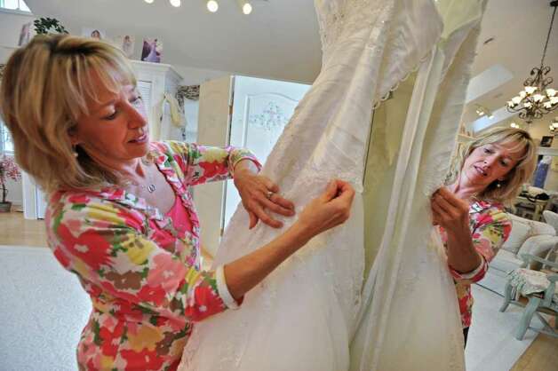 Dianne Kelder dress maker and owner of DeAnna's inspects a wedding dress 