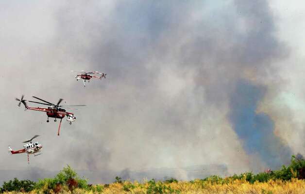 Helicopters leave after replenishing their water supply as they battle ...