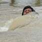 A man is nearly submerged as he crosses a flooded street using a.... photo: 1642163 slideshow 31095