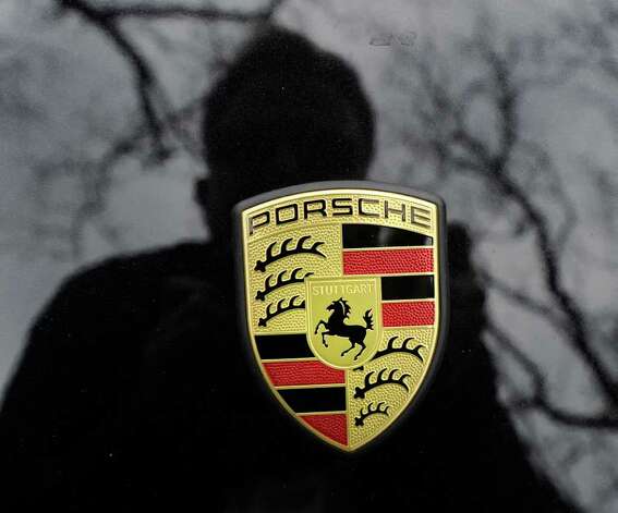 The Porsche emblem on the front end of a black Porsche convertible parked on