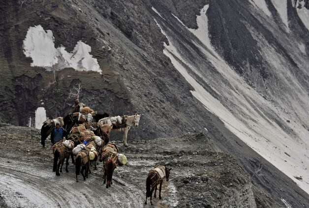 Kashmiri porters with their horses look on from the newly reopened Srinagar-Leh highway in Zojila Pass, about 67 miles east of Srinagar, on Wednesday. The 275-milehighway was opened for the season by Indian Army authorities after remaining snow at Zojila Pass, some 11,581 feet above sea level, had been cleared. The pass connects Kashmir with the Buddhist-dominated Ladakh region, a famous tourist destination among foreign tourists for its monasteries, landscapes and mountains. AFP PHOTO/Tauseef MUSTAFA Photo: TAUSEEF MUSTAFA, AFP/Getty Images / 2012 AFP