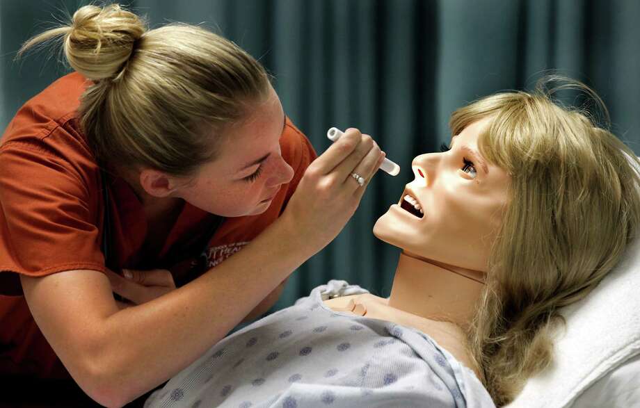 Nursing student Paige Adkins performs an evaluation on a programmable mannequin. She concedes working with - 920x920