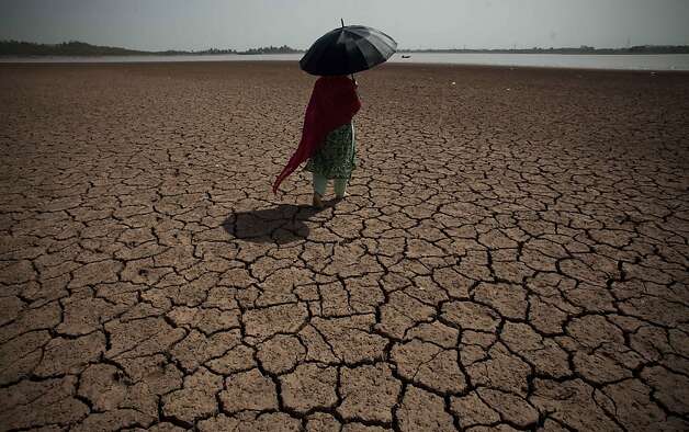 A woman shields herself from the sun as she crosses a parched landscape last year toward a water source that supplies Islamabad and Rawalpindi in Pakistan. Photo: B.K. Bangash, Associated Press