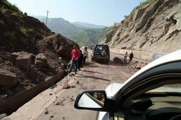 Vehicles make their way slowly along the road after a rock-fall in Yiliang, southwest China's Yunnan province on Friday following two shallow quakes that struck the remote and mountainous border area of Yunnan and Guizhou province of southwest China.   Dozens of people were killed and 550 injured when two shallow quakes with a magnitude of both at 5.6 struck a remote and mountainous area of southwest China, toppling buildings and sparking chaos in the streets, officials said.      ( AFP/AFP/GettyImages) Photo: AFP, Ap/getty / 2012 AFP