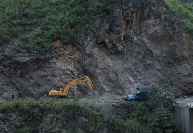 An excavator clears a road after a rock-fall in Yiliang, southwest China's Yunnan province on Friday, following two shallow quakes that struck the remote and mountainous border area of Yunnan and Guizhou province of southwest China.  Dozens of people were killed and 550 injured when two shallow quakes with a magnitude of both at 5.6 struck a remote and mountainous area of southwest China, toppling buildings and sparking chaos in the streets, officials said.  ( AFP/AFP/GettyImages) Photo: AFP, Ap/getty / 2012 AFP