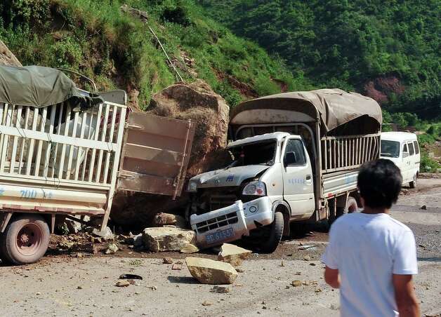 A man looks at the trucks damaged by fallen rocks after an  earthquake in Zhaotong town, Yiliang County, southwest China's Yunnan Province, Friday. A series of earthquakes collapsed houses and triggered landslides Friday in a remote mountainous part of southwestern China where damage was preventing rescues and communications were disrupted. At least 64 deaths have been reported. (AP Photo) Photo: Associated Press / SL
