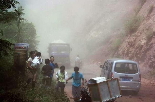 People run as rocks fall near their vehicles after the area was hit by an earthquake in Zhaotong town, Yiliang County, southwest China's Yunnan Province, Friday. A series of earthquakes collapsed houses and triggered landslides Friday in a remote mountainous part of southwestern China where damage was preventing rescues and communications were disrupted. Dozens of deaths have been reported. (AP Photo) Photo: Associated Press / SL