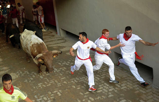 Participants run in front of Dolores Aguirre's bulls during a bull run of the San Fermin Festival in Pamplona, northern Spain, on July 8, 2013. The festival is a symbol of Spanish culture that attracts thousands of tourists to watch the bull runs despite heavy condemnation from animal rights groups. Photo: PEDRO ARMESTRE, AFP/Getty Images / 2013 AFP
