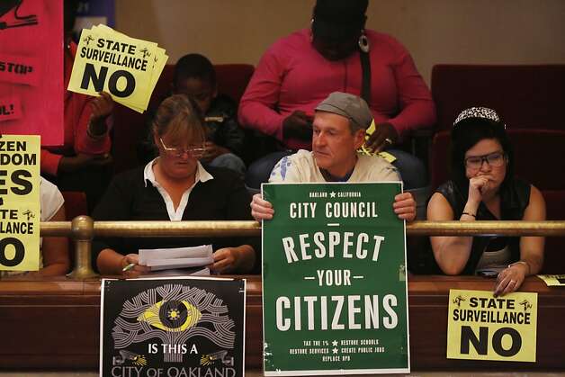 Audience members hold signs protesting the Domain Awareness Center during a city council meeting at the Oakland City Hall in Oakland, Calif. on July 30, 2013. Photo: Ian C. Bates, The Chronicle