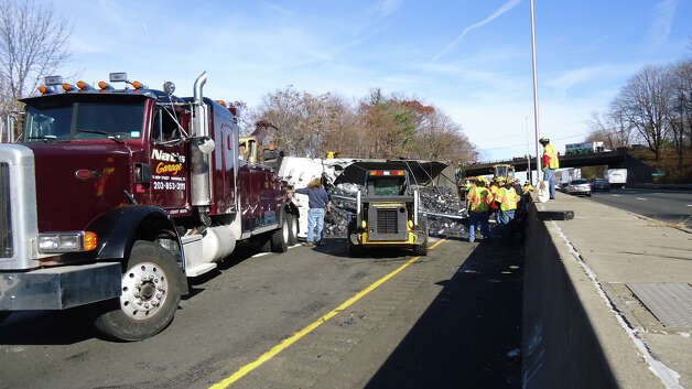 Workers clear debris spilled across all three lanes of Interstate 95, between southbound Exits 14 and 13, on Wednesday morning after a truck overturned and spilled its load of scrap metal. Photo: Norwalk Fire Department / Norwalk Citizen contributed