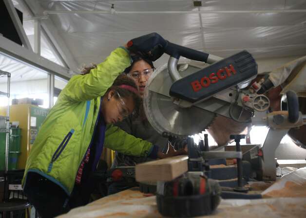 Mikaela James, 9, gains guidance from architect Emily Pilloton while using a miter saw during a class on how to fix things. Photo: Leah Millis, The Chronicle