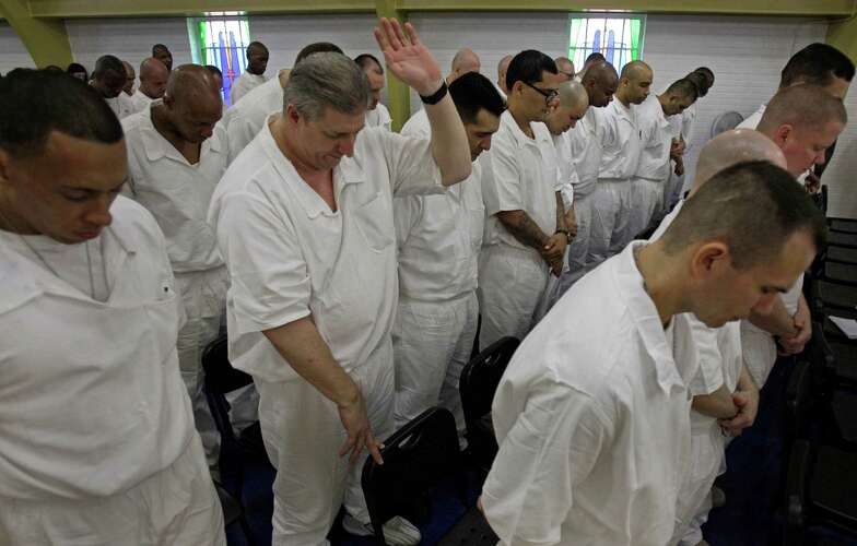 Prisoners at the Texas Department of Criminal Justice's Darrington Unit, 59 Darrington Unit Road, pray during a Convocation ceremony    Monday, Aug. 29, 2011, in Rosharon. Texas prison officials, Houston lawmakers and representatives of Southwestern Baptist Theological Seminary celebrated the opening of the state's first 4-year prison seminary program.   The nondenominational program, sponsored by the TDCJ, Southwestern Baptist Theological Seminary, Southern Baptists of Texas Convention and the Heart of Texas Foundation, will train inmates who are serving lengthy sentences to become ministers. Once they graduate from the program, the inmates will go to other Texas prison facilities where they will minister to their fellow offenders.  ( Melissa Phillip / Houston Chronicle )