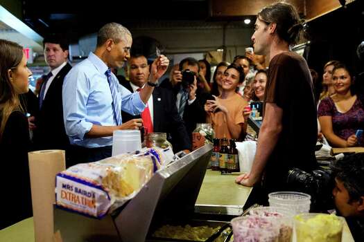 President Barack Obama scrutinizes his credit card as he jokes with the wait staff while ordering barbecue at Franklin Barbecue in Austin, Texas, Thursday, July 10, 2014. Austin is the final leg in his three city trip before returning to Washington. (AP Photo/Jacquelyn Martin) Photo: Jacquelyn Martin, Associated Press / AP