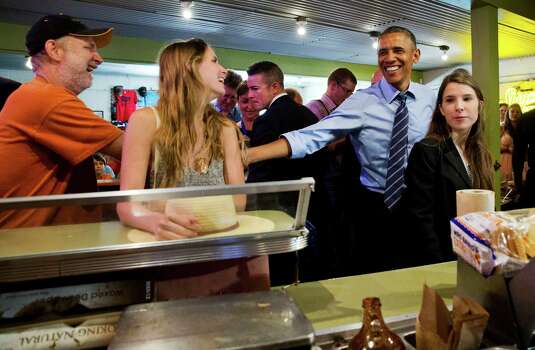 President Barack Obama jokes with patrons as he orders barbecue for himself and the people in the front of the line at Franklin Barbecue in Austin, Texas, Thursday, July 10, 2014. Austin is the final leg in his three city trip before returning to Washington. At right is Kinsey Button, who introduced the President in his speech earlier that afternoon. (AP Photo/Jacquelyn Martin) Photo: Jacquelyn Martin, Associated Press / AP