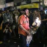 A man burns an effigy of Royals player near the intersection of 19th and Mission Street after the Giants win the seventh game of the World Series on Wednesday, October 29, 2014.