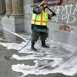 Stephen Lee, from the Department of Public Works, removes graffiti on a Mission Street business in San Francisco, Calif. on Thursday, Oct. 30, 2014. The celebration turned ugly when crowds became unruly and vandalized several businesses and vehicles after the Giants beat the Kansas City Royals in the World Series.