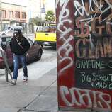 A woman walks past a business marred by graffiti on Mission Street in San Francisco, Calif. on Thursday, Oct. 30, 2014. The celebration turned ugly when crowds became unruly and vandalized several businesses and vehicles after the Giants beat the Kansas City Royals in the World Series.