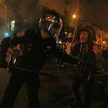 A riot police officer tries to tame the scene after Giants fans riot in the streets at 22nd and Mission after the San Francisco Giants win the World Series against the Kansas City Royals Wednesday, October 29, 2014.