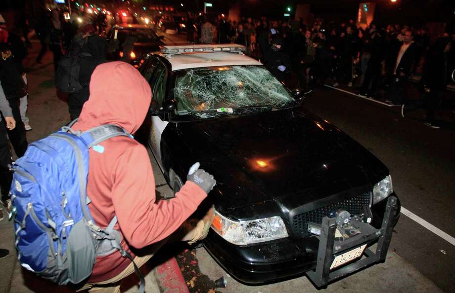 A demonstrator kicks a police car during a protest in Berkeley, Calif. Sunday, December 7, 2014 shining light on the chokehold death of Eric Garner in New York City and the shooting of Mike Brown in Ferguson, Missouri. Photo: Jessica Christian / The Chronicle / ONLINE_YES