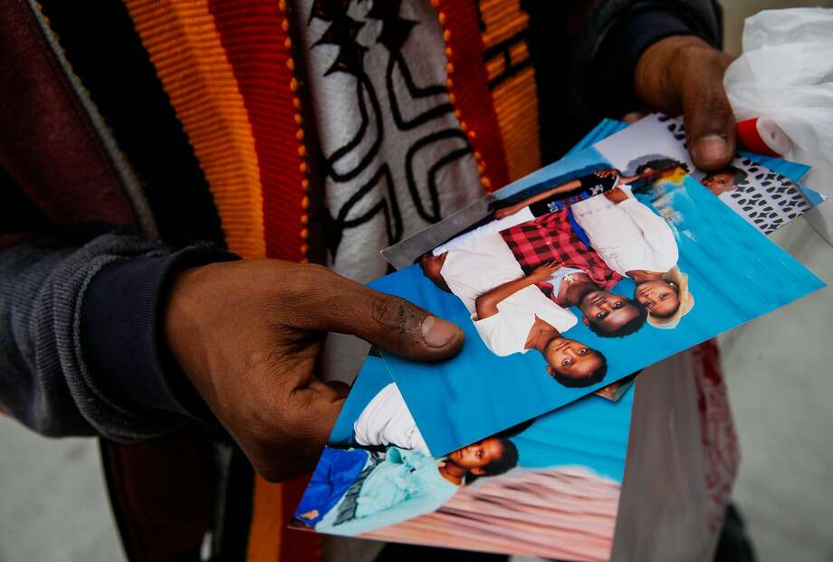 Fikre Atnafe looks through photos of the family of Yonas Alehegne, an Ethiopian immigrant who was shot and killed by an Oakland police officer in August, at a candlelight vigil for him in Oakland, Calif., on Sunday, September 13, 2015. Photo: Sarah Rice, Special To The Chronicle
