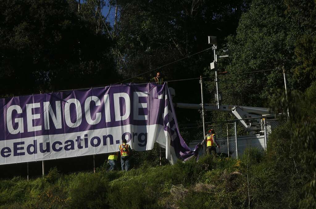 Workers hang a banner that says “Armenian Genocide 1915” over I-80 westbound on Treasure Island along the Bay Bridge. Photo: Leah Millis, The Chronicle