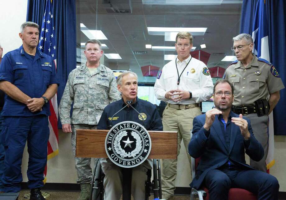 Gov. Greg Abbott gives a briefing at the State of Texas Emergency Command Center on Sunday in Austin. Left to right are U.S. Coast Guard Commander Karl Schultz; Maj. Gen. John F. Nichols, in the National Guard; Abbott; Nim Kidd, chief of the Texas Division of Emergency Management; Steven McCraw, director of the Texas Department of Public Safety; and interpreter Alan Sessions. Abbott mobilized the entire National Guard on Monday to help with the disaster wrought by Harvey. Photo: Suzanne Cordeiro /AFP /Getty Images / AFP or licensors