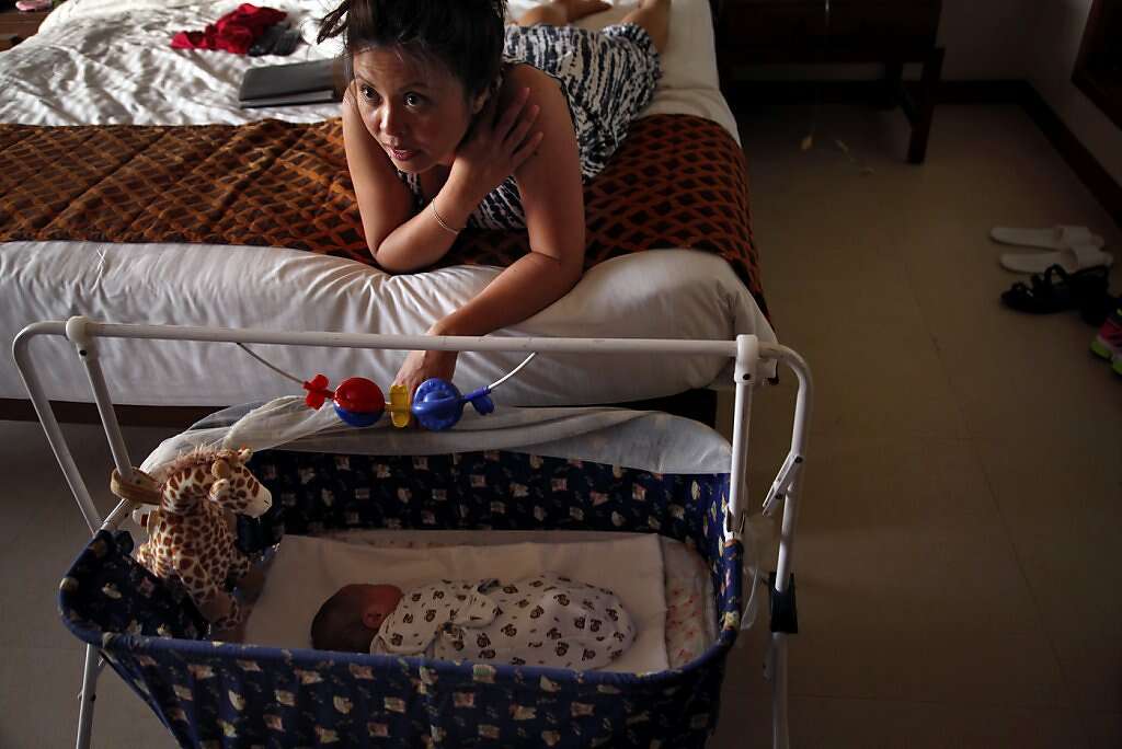 Jennifer Benito-Kowalski watches television as baby Kyle sleeps in their room at the Madhubhan Resort and Spa in Anand, India, Friday, May 24, 2013. Photo: Nicole Fruge, The Chronicle