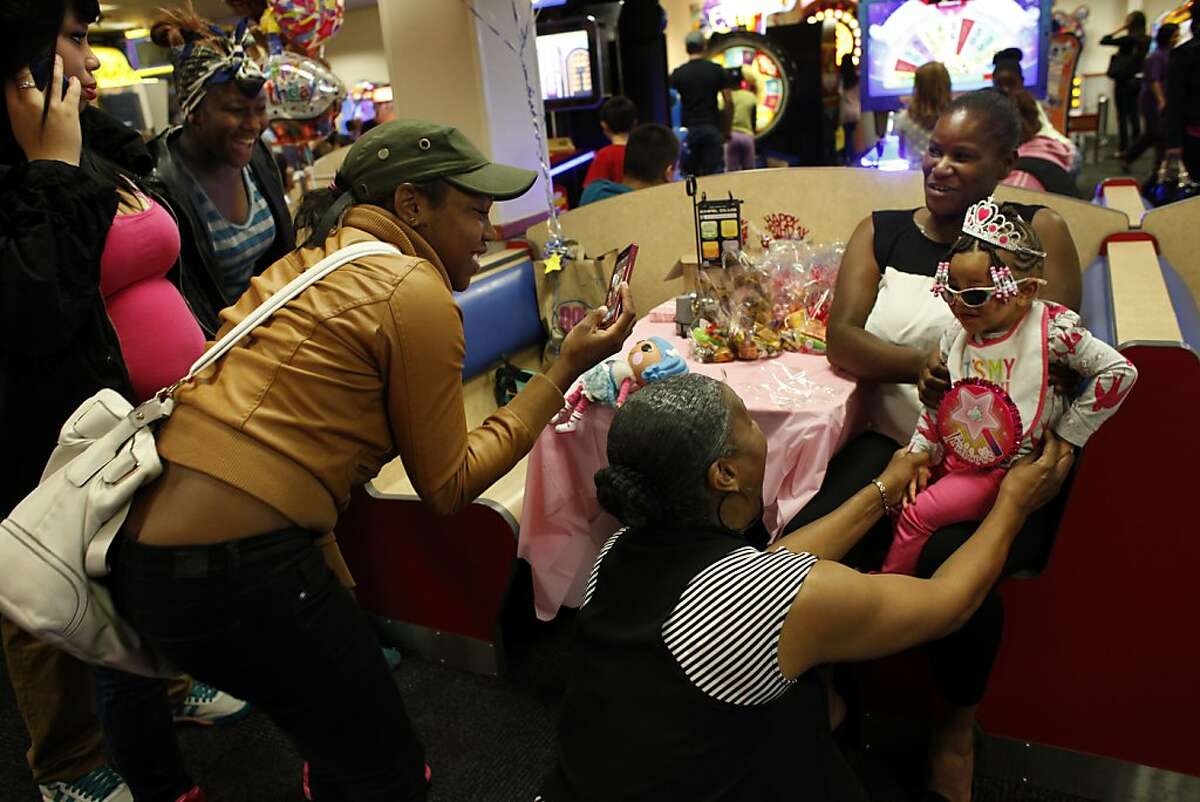 Brijjanna Price, left, tries to get in touch with her father while other family members take LaMya Deshana's picture as the birthday princess for her first birthday party at Chuck E. Cheese's, Saturday, November 9, 2013, in Hayward, Calif. Photo: Lacy Atkins, The Chronicle
