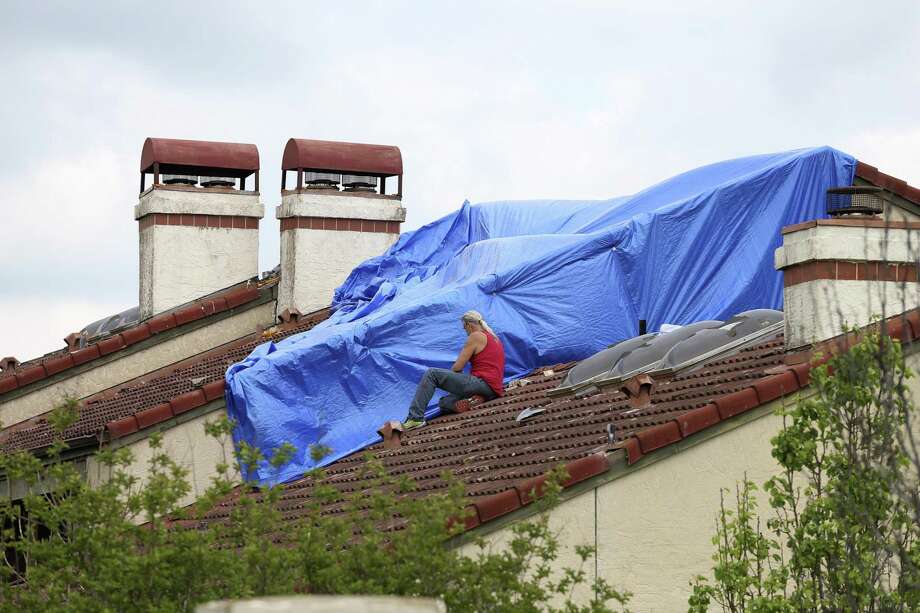 A worker protects a roof at The Village at Woodlake in April 2016 after a major hail storm near Helotes. The Texas Senate approved a bill Tuesday that would require plaintiff attorneys to file a detailed notice more than 60 days before a lawsuit regarding storm damage claims is filed or risk forfeiting attorneys’ fees in the case. Photo: JERRY LARA /San Antonio Express-News / © 2016 San Antonio Express-News